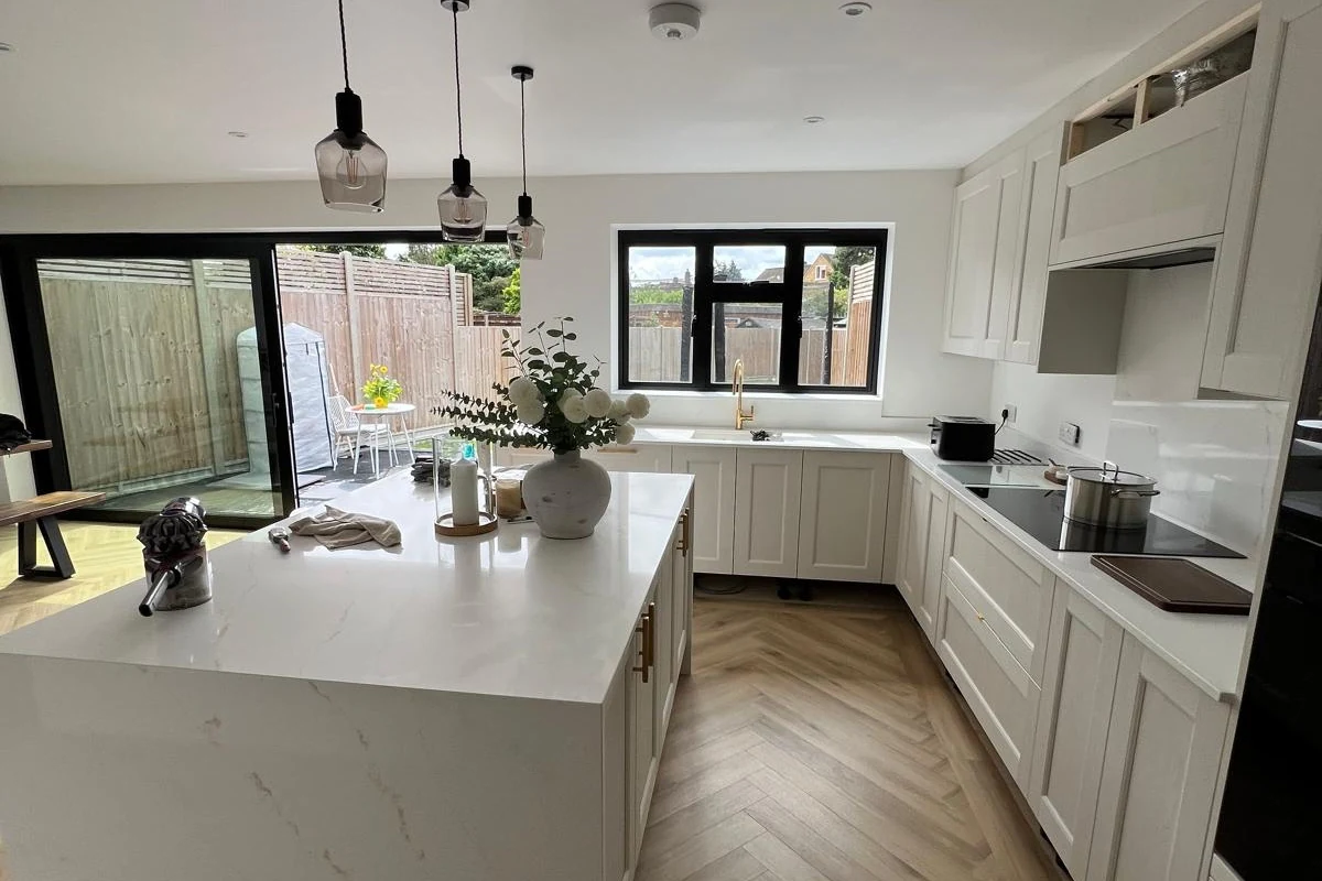 White quartz island with mitred waterfall ends in a fitted shaker kitchen